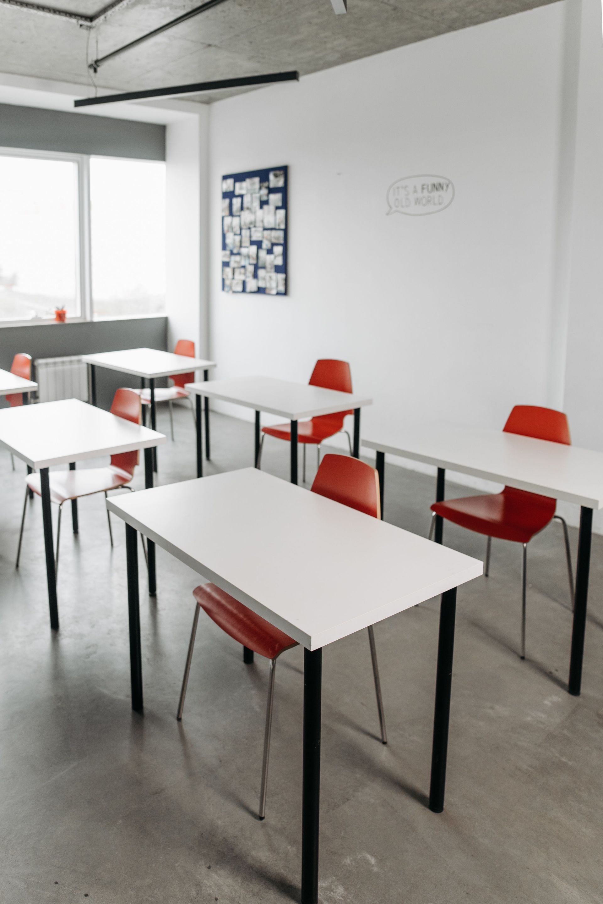 Contemporary classroom interior with red chairs and white desks arranged in rows.